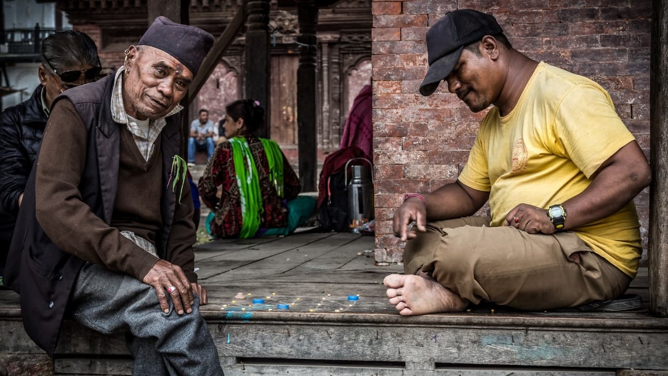 Nepalese elderly man and younger man are playing a board game.